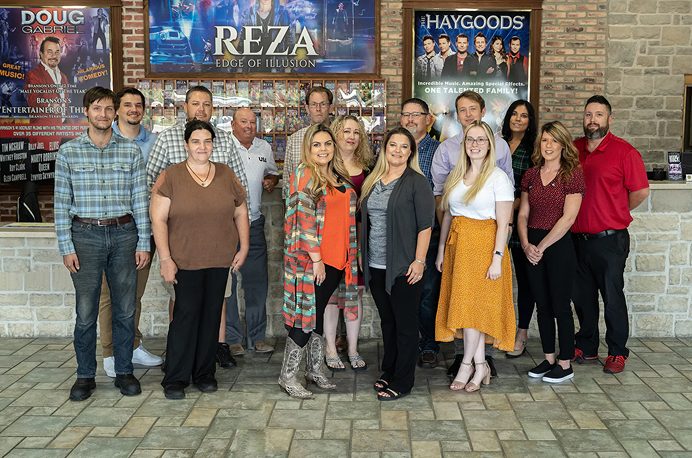 The VacationBranson.com team in front of the show posters at the welcome center
